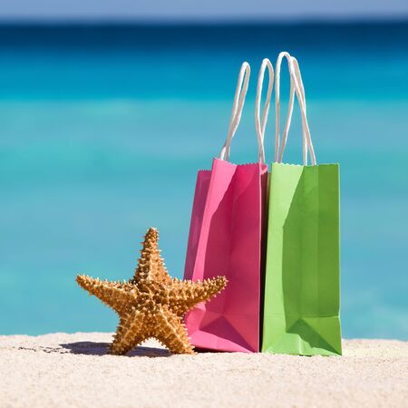 Shopping bags and starfish on sand against turquoise caribbean sea water. Tropical celebration on beach 
の写真素材