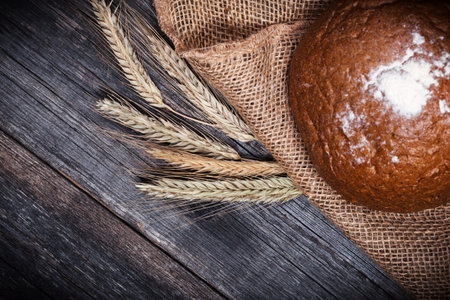 Fresh round bread on black wooden board, top view with copyspace