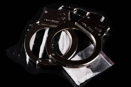 Handcuffs and cocaine on black backgroundの写真素材