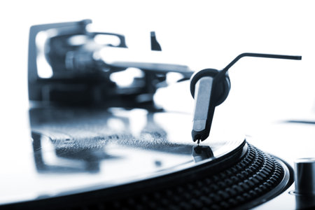 DJ headshell on spinning record, closeup. Blue tone