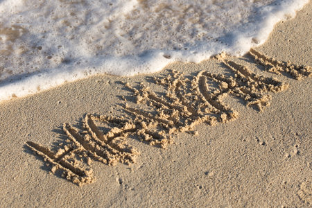 Inscription Hawaii on sandy beach with wave's foam, free copyspaceの写真素材
