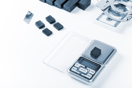 Blocks of hashish on digital scales over white background. Drug dealer is arrested in process of weighing hash for illicit deal. Blue toneの写真素材