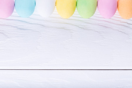 Empty rustic wooden white background, decorated colorful pastel easter eggs. Top view with copyspace. Happy Easter cardの写真素材
