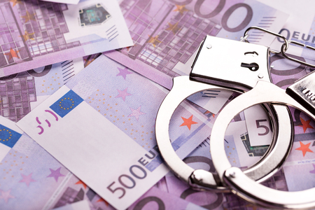 Pair of handcuffs closeup on euro banknotes background. Corruption problem in the worldの写真素材