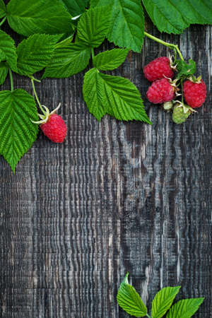 Old wooden board decorated raspberry and leavesの写真素材