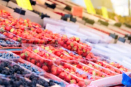 Strawberry and blueberry on green grocery market, out of focus, blurred imageの写真素材