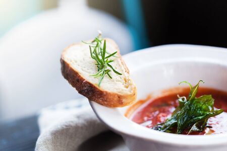 Italian Tomato soup in bowl with slice of bruschetta decorated fresh rosemary leaf. Nobody, shallow depthの写真素材