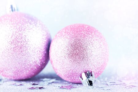 Pink Christmas baubles on silver glitter with sparkling defocused lights on background, New Year greeting card. Shallow depth of field.の写真素材