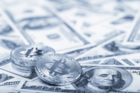 Bitcoins on dollar banknotes background, closeup 