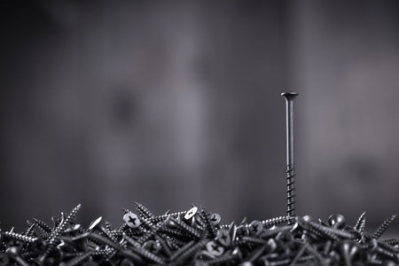 Pile of black screws closeup on wooden background