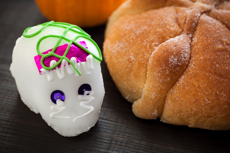Dia De Los Muertos (Day of the Dead) Sugar Skull ( Calaverita) and bread of Dead Offering, on wooden table, selective focusの写真素材