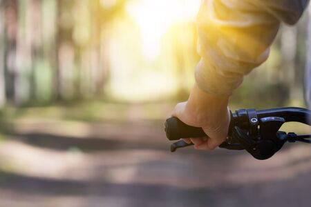 Woman riding a mountain bicycle along path at the forest. Closeup on handlebar with female hand. Healthy lifestyle and sport conceptの写真素材