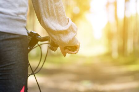 Woman riding a mountain bicycle along path at the forest. Closeup on handlebar with female hand. Healthy lifestyle and sport conceptの写真素材