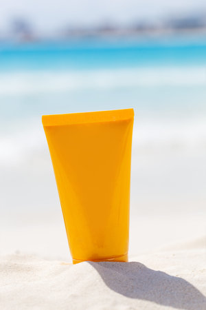 Face care travel concept. Sunscreen lotion on sandy beach with sea background