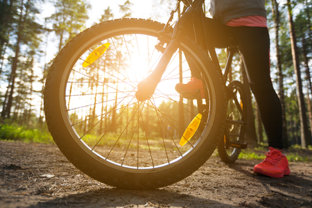 Woman riding a mountain bicycle along path at the forest. Closeup on wheel with spokes. Healthy lifestyle and sport concept の写真素材