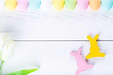Colorful pastel easter eggs on rustic wooden white background, decorated rabbits and flowers. Happy Easter cardの写真素材