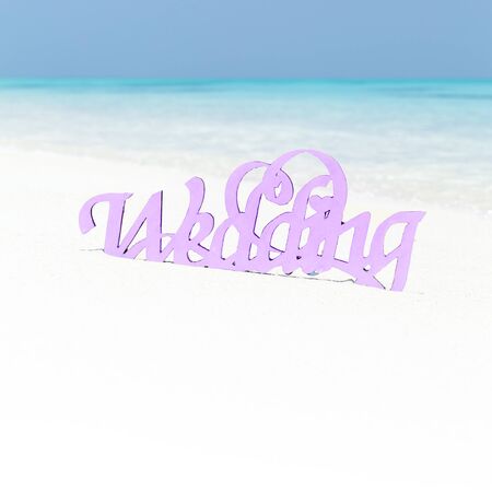 White wooden decorative word WEDDING on sandy beach, marriage greeting cardの写真素材