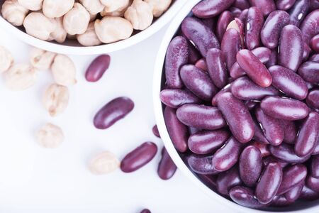 Raw dry chickpeas and red beans in bowl on white background, healthy vegan food with a lot of proteinの写真素材