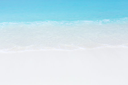 Tropical beach scene of azure crystal sea with soft waves, wild untouched seashore with copy space.