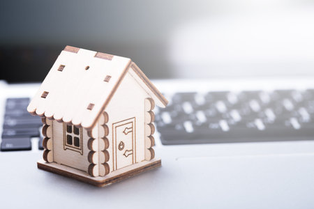 Real estate and property concept. Wooden model of house on laptop keyboard