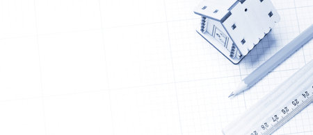 Planning design of new project. Wooden model of house, pencil and ruler on plotting paper. Blue tone