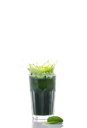 Green fresh spinach smoothie with splash in glass on white backgroundの写真素材