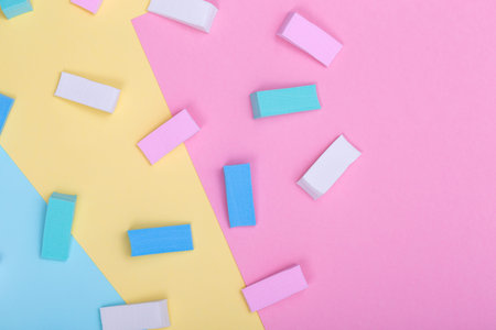 Different pastel color sponges for cream foundation on pastel colored paper texture, flat lay