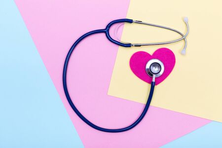 Stethoscope on heart shape over pastel colored paper texture, flat lay
の写真素材