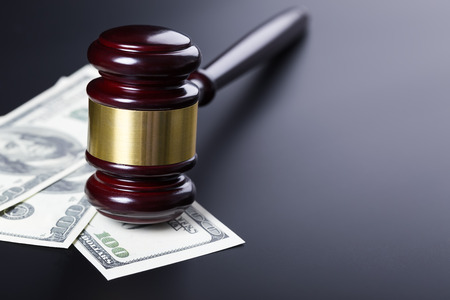 Wooden judge gavel on hundred dollar banknotes closeup over black backgroundの写真素材