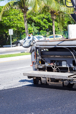 Pavement truck laying fresh asphalt  during road construction