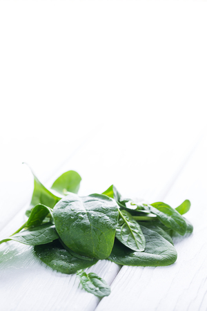 Fresh raw ordanic baby spinach on white wooden board, diet conceptの写真素材