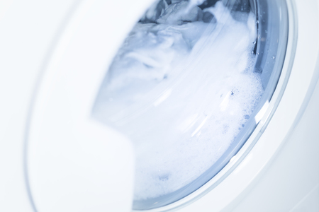 Process of cleaning white cloth in washing machine, stainless drum inside with wet towels, closeup, nobodyの写真素材