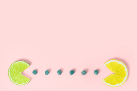 Lemon and lime fruits eating green peas on creative color paper background. Trendy minimal pop art style. Concept of funny colorful food.の写真素材