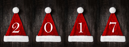 Santa Claus helper hats with sign 2017 on rustic wooden background. Christmas and New Year celebrationの写真素材