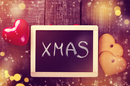 Christmas greeting card with blackboard and handmade cookies on dark wooden texture, top viewの写真素材