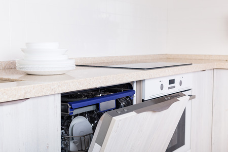 Kitchen with open dishwasher and clean white plates on countertop, light minimal modern interior, nobodyの写真素材