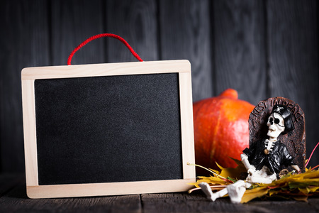 Halloween toy of skeleton with grave and chalkboard on wooden background, nobodyの写真素材