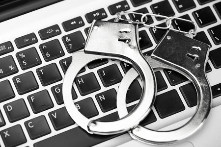 Handcuffs on laptop keyboard. Hacker cyber attack. Closeupの写真素材
