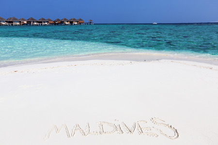 Handwriting word "Maldives"  on maldivian beach drawn on sand, travel destinations concept cardの写真素材