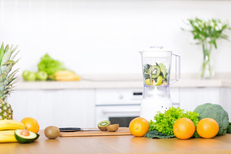 Young caucasian blond woman preparing detox fruits smoothie in blender on white kitchen, healthy eating, cooking, vegetarian food, dieting conceptの写真素材