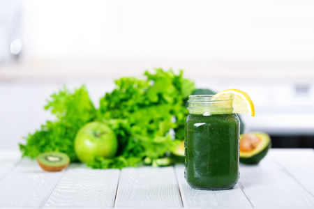 Detox smoothie cocktail with green fresh vegetables and fruits on white kitchenの写真素材
