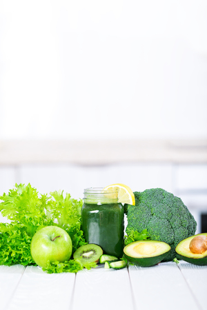 Detox smoothie cocktail with green fresh vegetables and fruits on white kitchenの写真素材