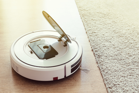 Robot vacuum cleaner cleaning laminate floor in room, nobodyの写真素材
