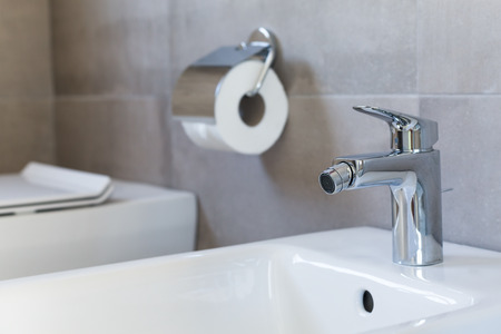 White ceramic bidet at modern restroom interior on toilet paper background, closeupの写真素材