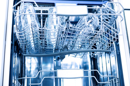 Empty dishwasher with opened door, home appliance dishwashing machine in kitchen interior, no people