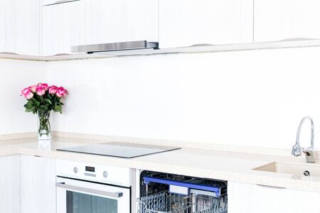 Empty dishwasher with opened door and beautiful bouquet of flowers roses, concept of present surprise for housewife, no peopleの写真素材