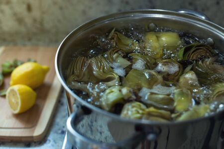 Cleaned artichokes preparing in metal pan on cooker, artichoke cooking process at kitchen interior, nobodyの写真素材