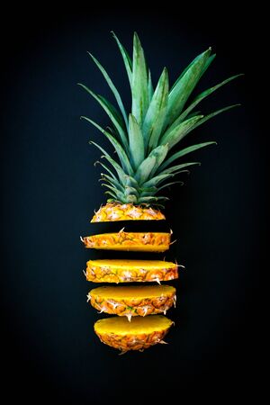 Sliced pineapple flying on dark background. Minimal food concept with summer fruits.の写真素材