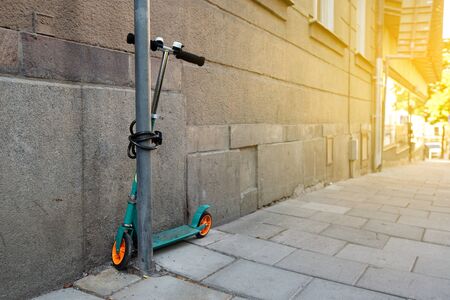 Green scooter locked at the street. Nobodyの写真素材