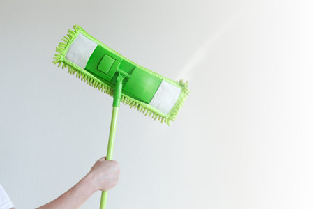 Home, housekeeping concept. Household equipment -  green mop in hand, closeup on white background...